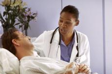 Photograph of a female doctor talking to a male patient in a hospital bed